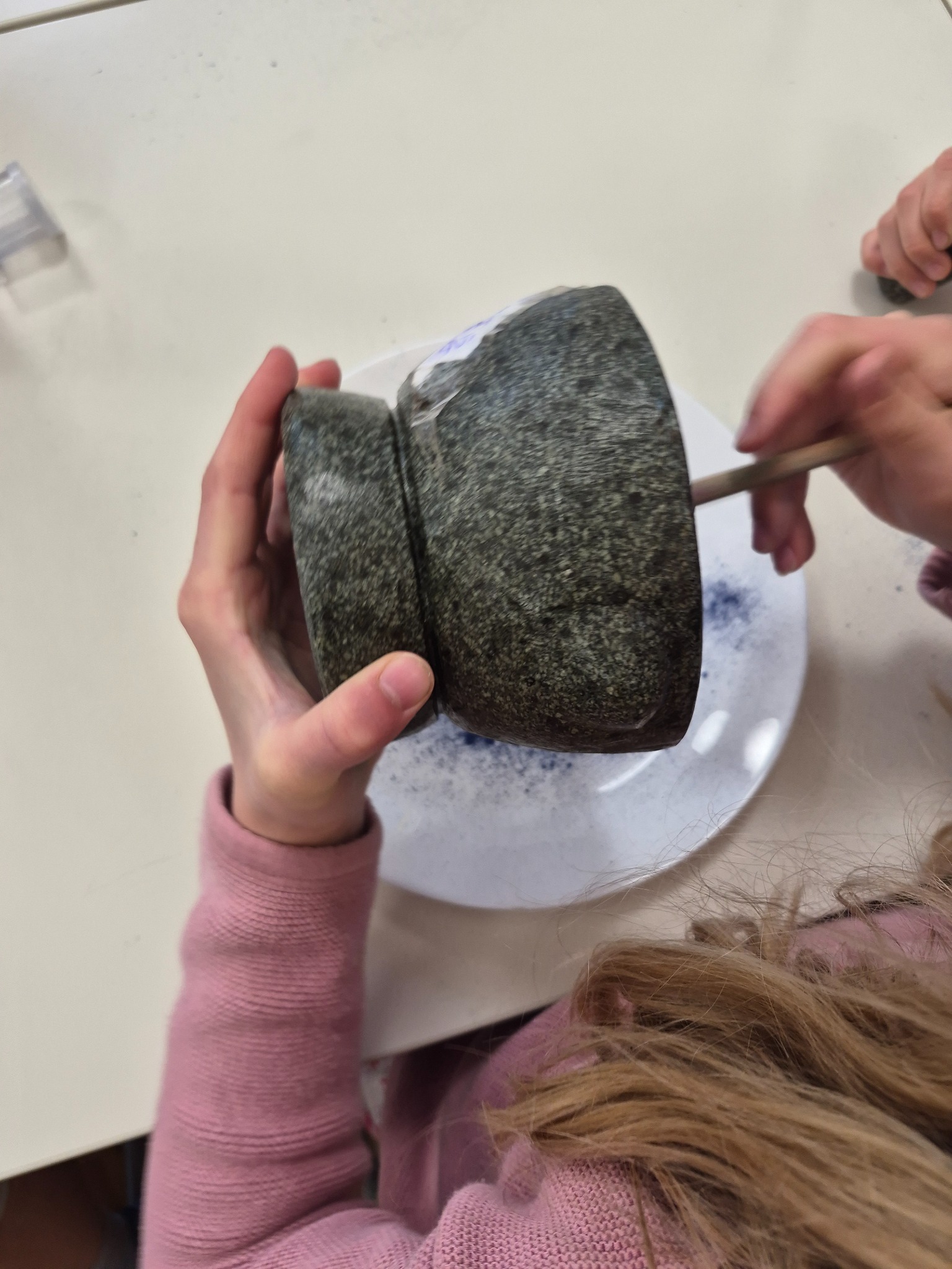 Child grinding natural pigment with a stone mortar