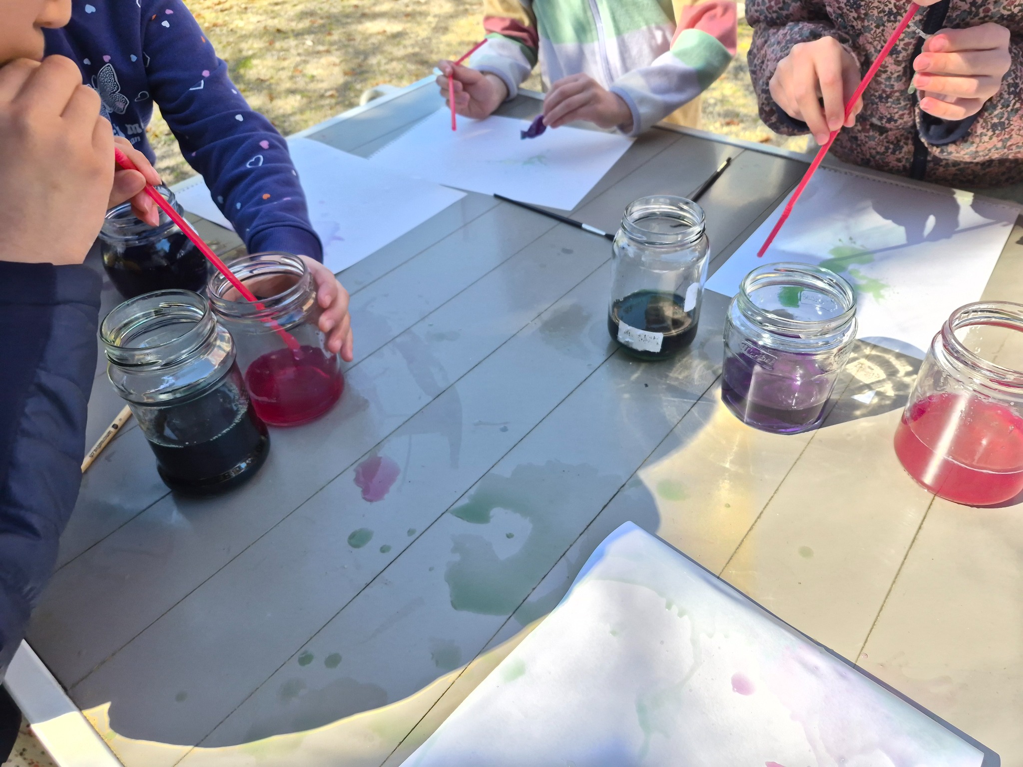 Children testing colourful botanical liquids outdoors